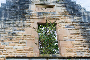 Window opening on abandoned building made of sandstone with engraved year 1890