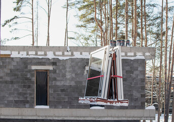 A crane lifts plastic windows at a construction site
