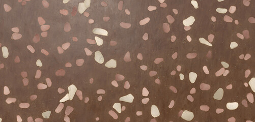 Closeup of a brown terrazzo floor with pink and white chips, creating a textured and patterned surface, ideal for backgrounds and design elements