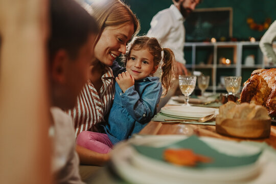 Happy family celebrating thanksgiving dinner, mother hugging daughter