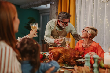 Family toasting during thanksgiving dinner with roasted turkey