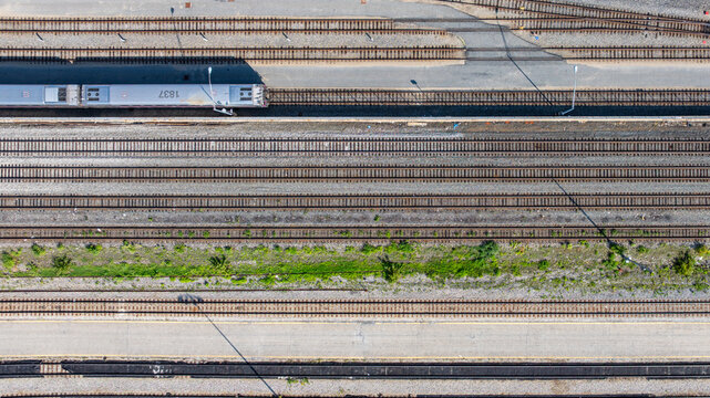 Straight down aerial view of several, many, parallel railroad tracks in a rail yard with a single train.