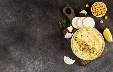 Lupini hummus with herbs, crackers, lemon on dark background.Healthy vegan snack.Top view.Copy space
