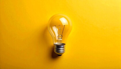 A transparent glass bulb rests on a vibrant yellow background, creating a stark contrast. The lightbulb is centered