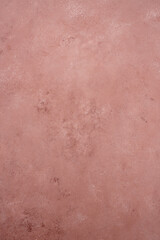 Pink plaster acquiring weathered texture on a rustic concrete wall