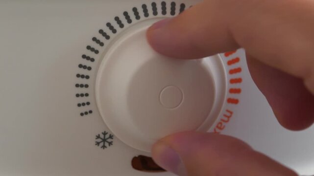 Regulator for heating cold water in boiler. Man turns temperature control on heater. Red light indicator comes on, boiler has turned on to heat water. Boiler heats water from cold water supply system