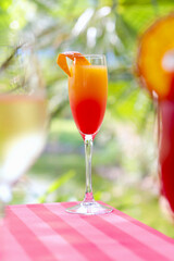 Non-alcoholic cocktail on background of palm trees. Refreshing drink. Tropical background. Concept of summer holidays. Vertical photo.