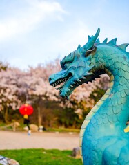 Teal dragon statue amidst spring blossoms