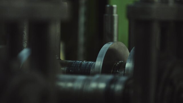 Close up of an industrial lathe machine automatically cutting threads on a metal rod during a manufacturing process in a factory, showing the rotating shaft and precision engineering in action