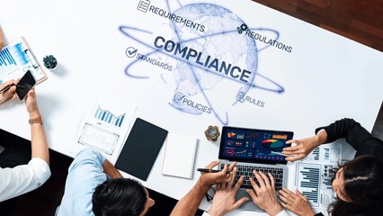 A diverse team collaborates on a compliance strategy, utilizing data visualizations and technology...