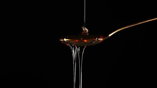 Spoon Full of Honey Against a Black Background Overflowing and Dripping
