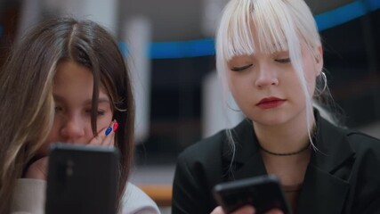 Close up view of high school girls operating phone while chatting indoors showing serious expressions reflecting digital lifestyle, communication and social interaction - Powered by Adobe