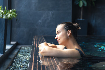 Woman leaning on pool edge with dreamy look. Calm pause.