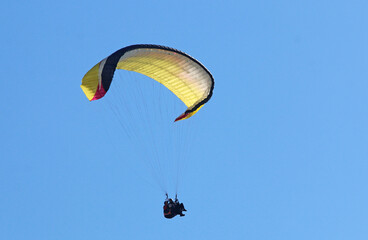 Tandem Paraglider flying in a blue sky	