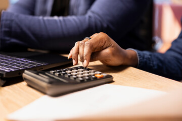 Married couple managing their bills and household payments at home, using calculator to do their financial planning and money management. Ensuring a secure financial future. Close up.