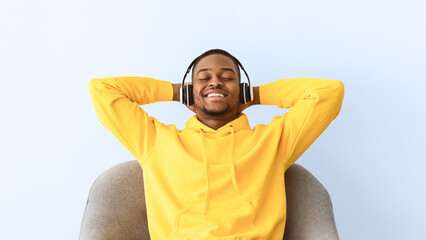 African American Guy Listening To Music Wearing Headphones Relaxing With Eyes Closed Sitting In...