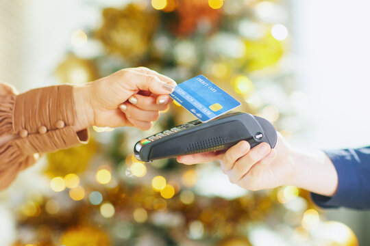 A woman, fatigued from heat, sits on living room floor, using handheld fan while powerful pedestal fan provides cool air. The scene emphasizes discomfort and need for relief from high temps - Powered by Adobe
