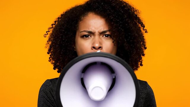 Woman with megaphone on orange backdrop. A striking portrait of anger and power. Expressing opinion, making announcement, raising awareness.
