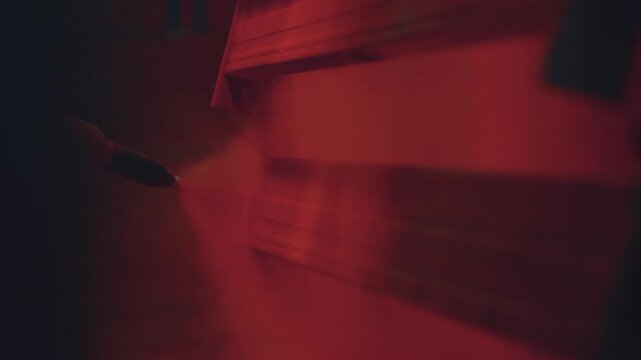 Close up view of an industrial spray gun applying red powder coating paint to a metal part on a production line, creating a durable and protective finish in a manufacturing workshop
