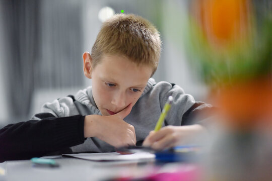 Preteen boy concentrating on schoolwork at home - Powered by Adobe