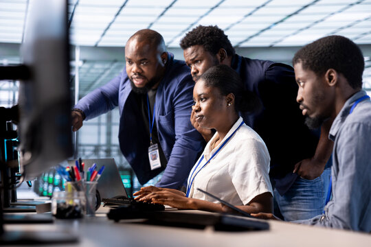Team of engineers reconfiguring server farm to optimize it for data processing requirements of customers. Coworkers collaborating to ensure data center equipment operates efficiently