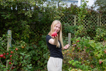 Young Person Offering Apple in Autumn Garden