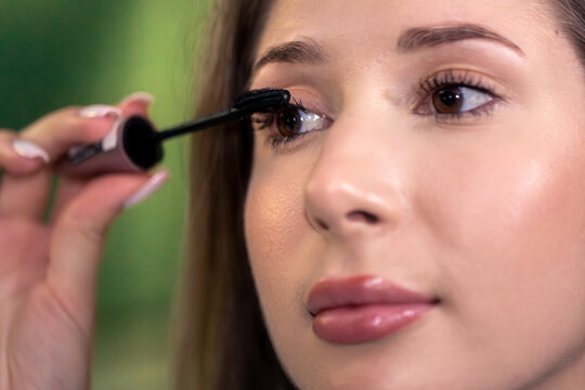 Young woman applying mascara closeup. GRWM lashes.