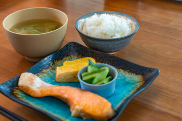 Japanese breakfast with grilled salmon, tamagoyaki, cucumber side dish, rice and miso soup
