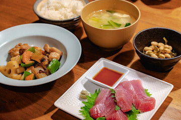Japanese dinner with tuna sashimi, stir-fried chicken and vegetables, simmered beans, rice and miso soup
