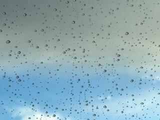 Water drops on car glass, rain drops on clear window. Raindrops falling on the glass of the car. Suitable for use in abstract backgrounds. Raindrops on the car window against the background of a sky. 
