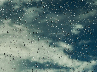 Water drops on car glass, rain drops on clear window. Raindrops falling on the glass of the car. Suitable for use in abstract backgrounds. Raindrops on the car window against the background of a sky. 