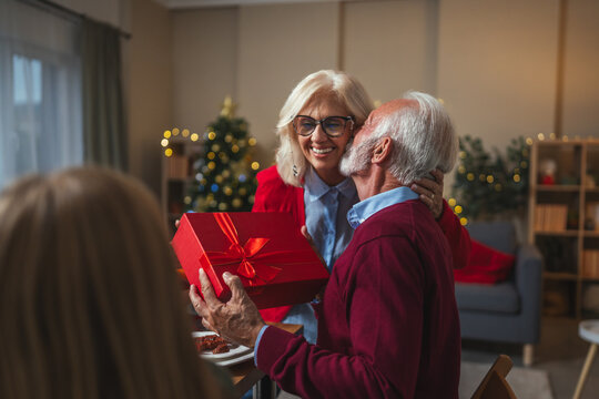 Senior couple celebrating christmas eve, exchanging present - Powered by Adobe