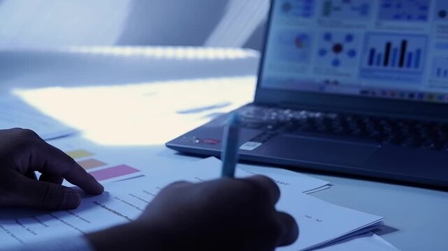 A person looks at a chart report on a laptop and then checks off the task list and budget list. Checks all the status checklist boxes and then signs it. The concept of checking and approving
