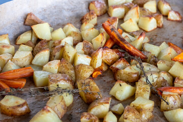 Roasted golden potatoes and carrots seasoned with herbs, arranged on a baking sheet, showcasing a delicious and healthy side dish for any meal or gathering