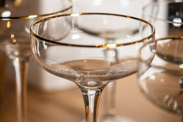Elegant glassware featuring delicate gold rim, showcasing a close-up view of crystal-clear cocktail glasses, perfect for upscale dining and celebratory occasions with refined aesthetics