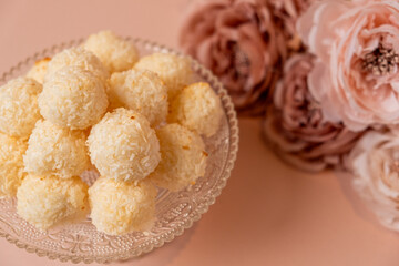 Delicious coconut balls arranged elegantly on a glass plate, surrounded by soft pastel flowers, creating a delightful dessert display for special occasions and celebrations