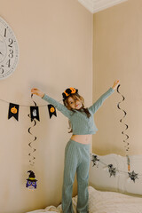 Little girl with hanging Halloween decor in the room.