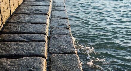 Stone steps meet the ocean waves creating a textured scene with water and stone elements visible close up