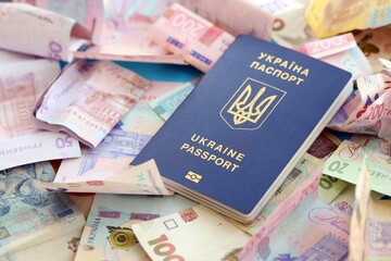 Ukrainian biometrical passport lies on big amount of different ukrainian hryvnia money bills