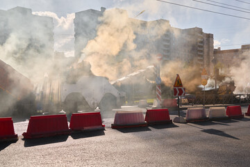 During the daytime, there is construction creating smoke and barriers affecting traffic in the city