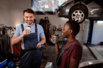Mechanics share a moment over coffee in a busy auto repair shop in the afternoon