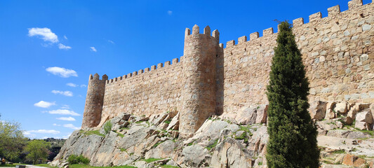 Medieval stone walls and towers of Avila fortress in Castile Spain under blue sky on sunny summer day