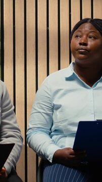 Vertical Video Anxious black woman job seeker getting called in the HR office to start interview, awaiting discussion and showcasing anticipation in office. People preparing for the recruitment