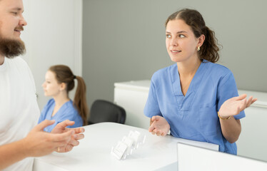 Fototapeta premium Dental clinic administrator talks to patients at the reception desk