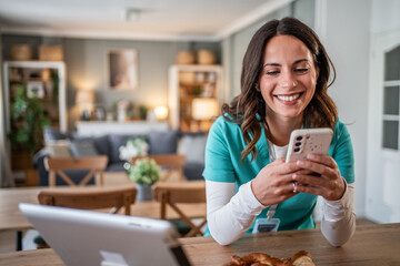 Smiling female nurse relaxing with smartphone at home