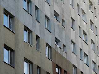 Facade of a concrete apartment building with repeating windows, symbolizing urban housing, city life, and minimalist architecture