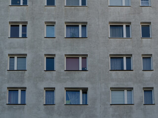 Fototapeta premium Concrete facade of an apartment block with repetitive windows, reflecting urban housing patterns and minimalist city architecture