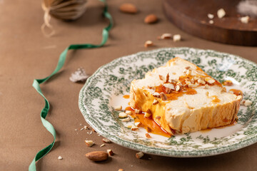 A slightly elevated shot captures a slice of traditional caramelized egg white pudding known as molotof or molotov, generously drizzled with golden syrup and sprinkled with almond pieces