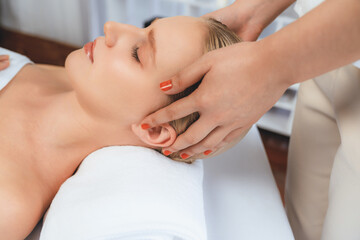 Fototapeta premium Closeup woman enjoying relaxing anti-stress head massage and pampering facial beauty skin recreation leisure in dayspa modern light ambient at luxury resort or hotel spa salon. Quiescent
