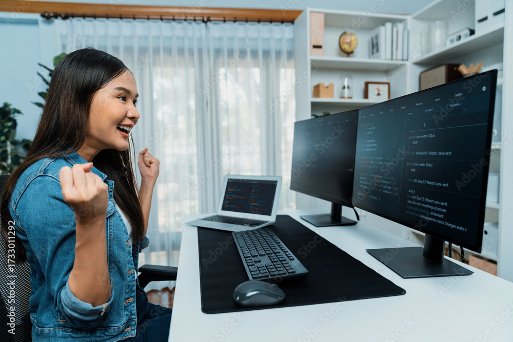 Wall mural young asian it developer creating raising fist up with successful information on pc with coding prog